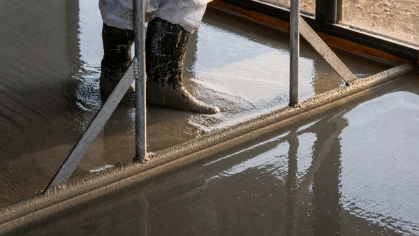Intérieur en cours de rénovation avec pose de revêtement de sol stratifié gris clair partiellement installé sur chape béton brute